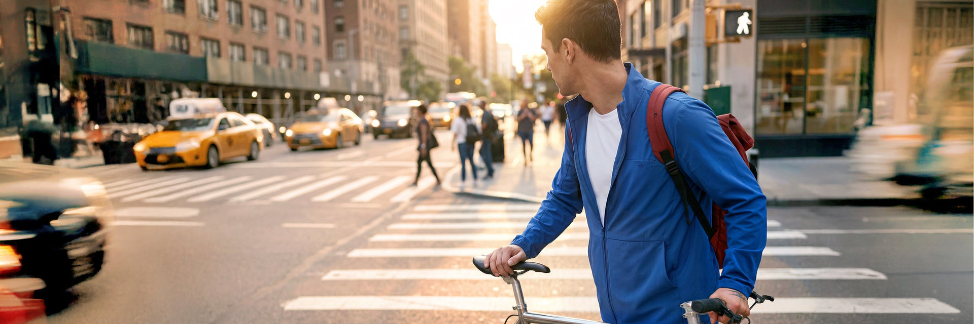 A male healthcare professional in light blue scrubs walking briskly along a busy city street