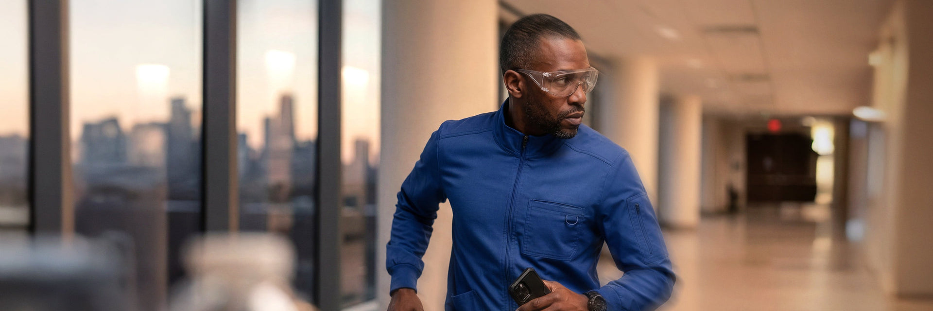 A male healthcare professional in bright blue scrubs walking energetically down a hospital corridor