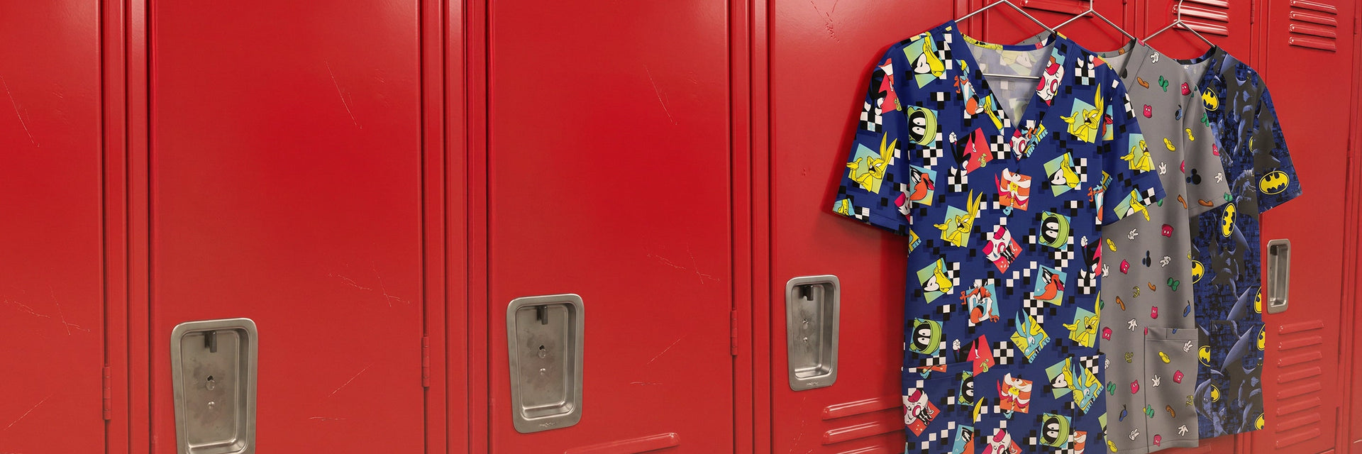 A display of brightly patterned print scrub tops in red tones hanging on red lockers in a staff room
